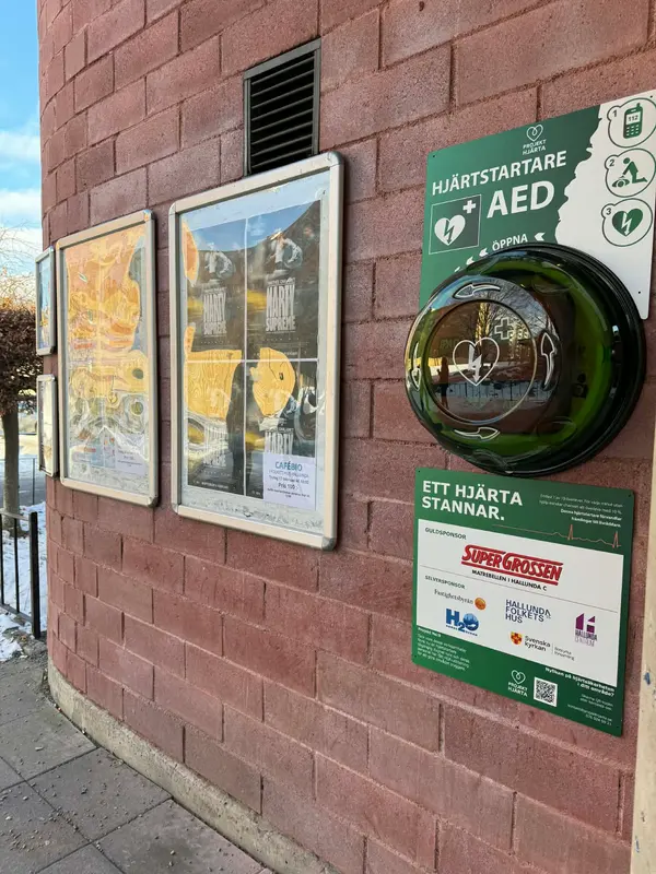 Hjärtstartare i runt skåp på tegelvägg vid Folkets hus i Hallunda