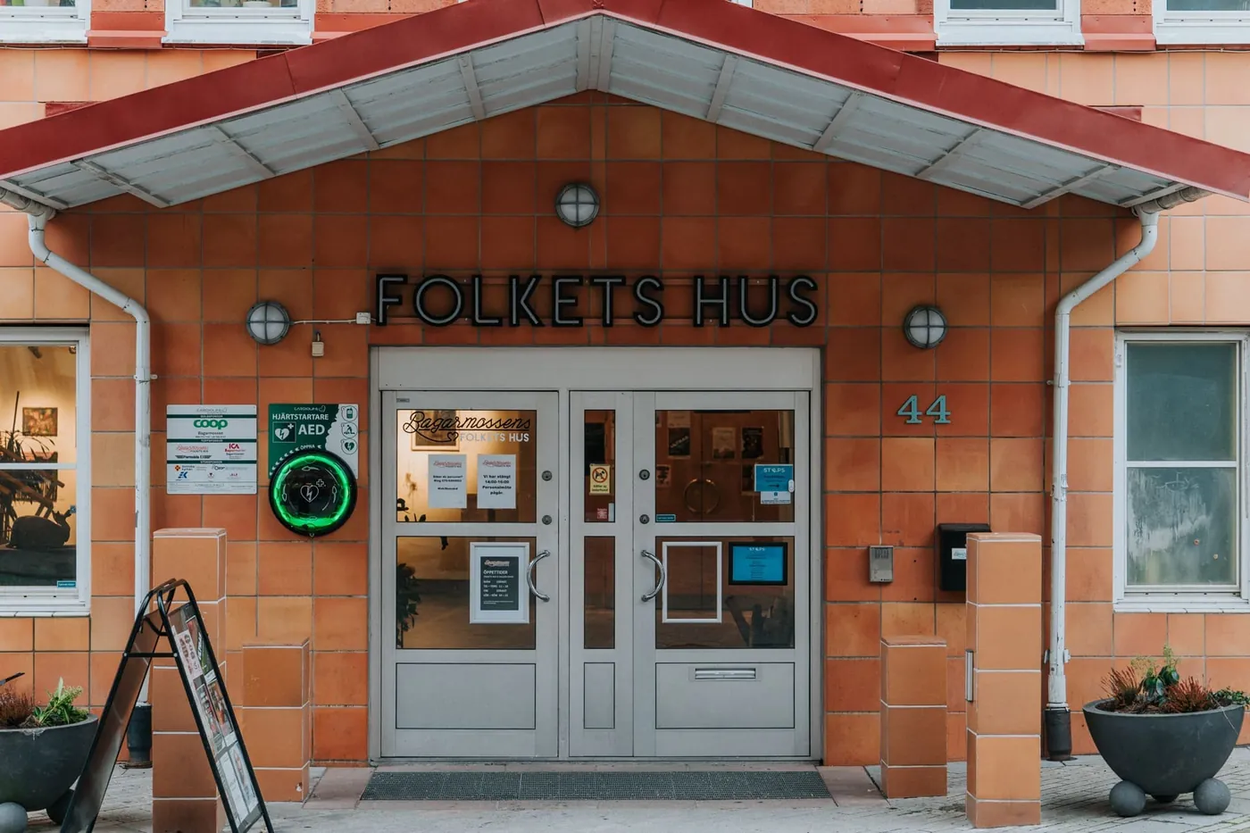 Hjärtstartare i grönt utomhusskåp bredvid entrén till Folkets hus i Bagarmossen