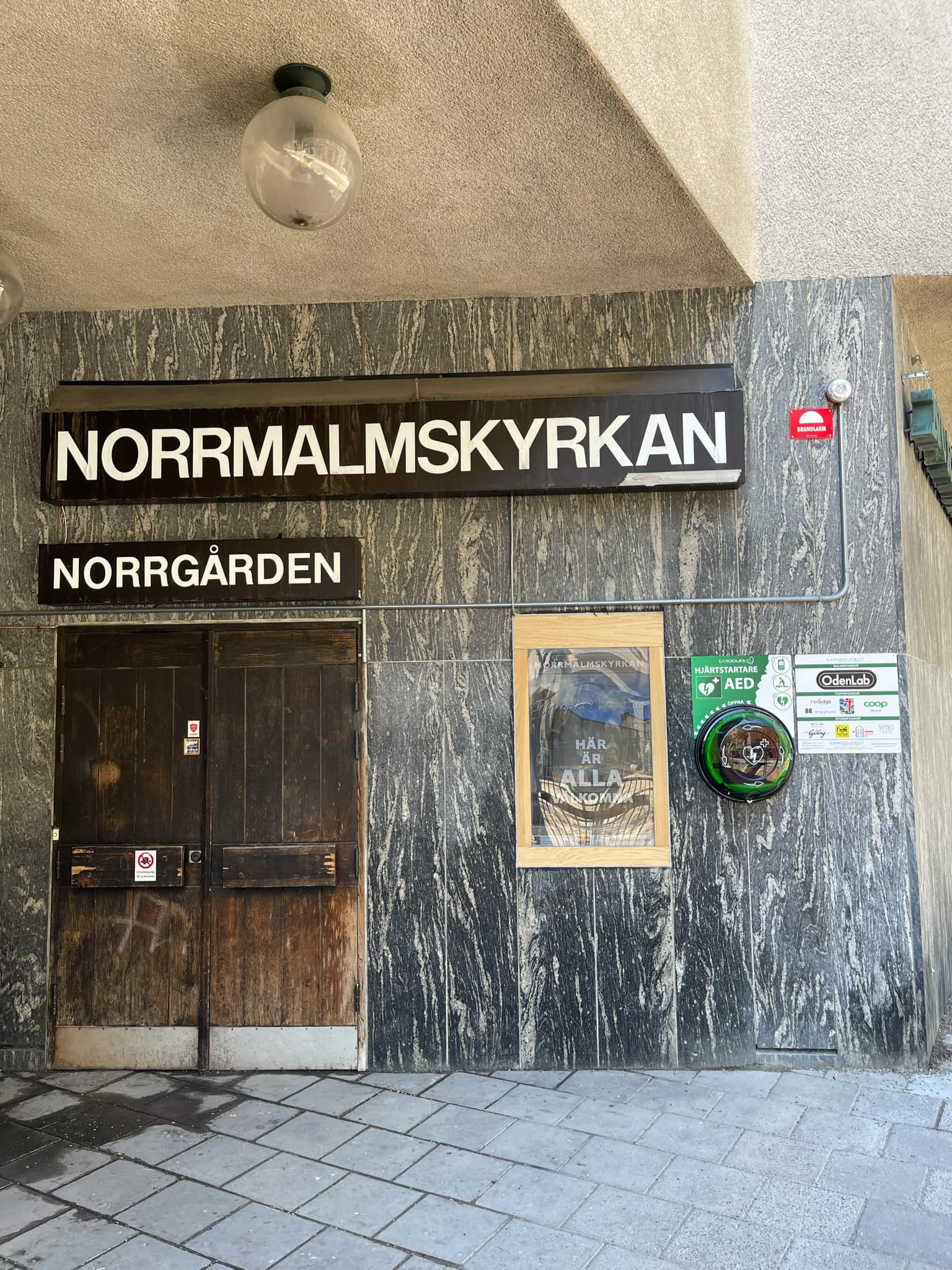 Hjärtstartare i skåp med sponsortavla, Norrmalms Baptistförsamling i Stockholm