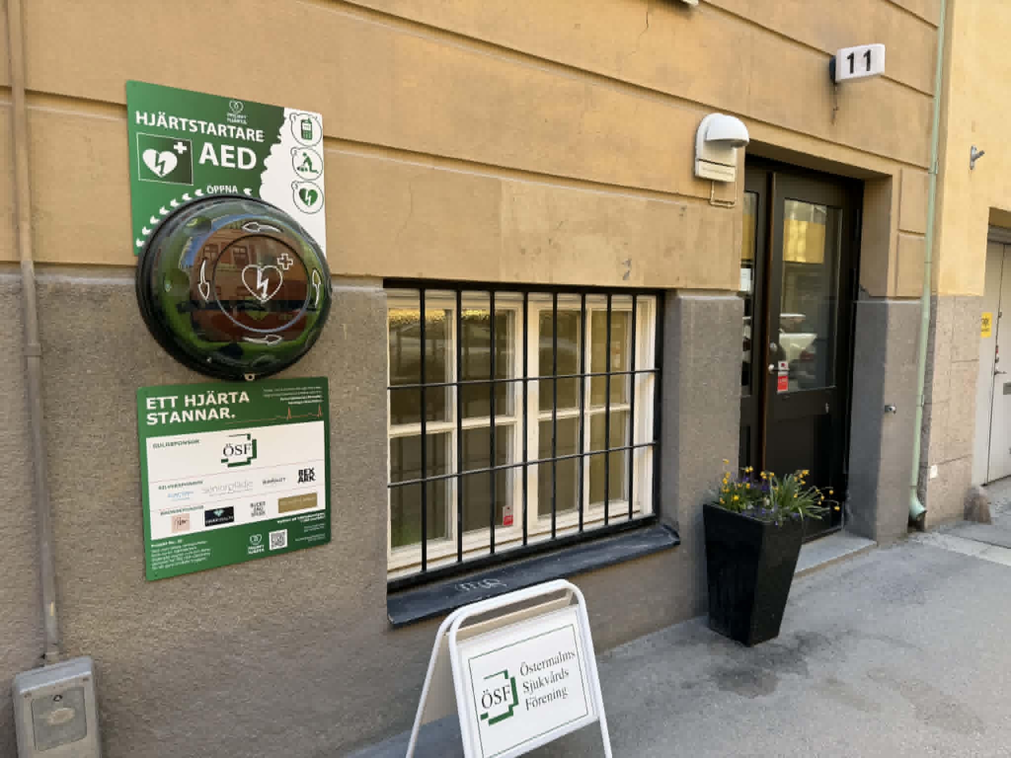 Hjärtstartare i skåp med sponsortavla, Östermalms Sjukvårdsförening i Stockholm